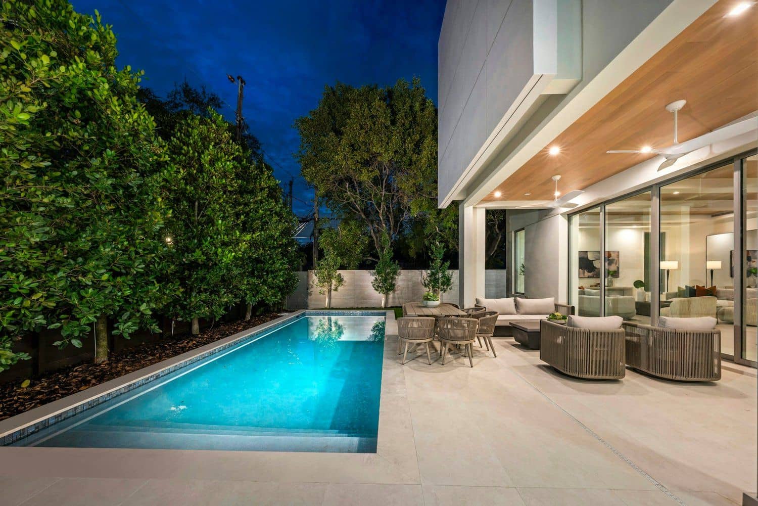 Backyard pool and patio at dusk with warm lighting