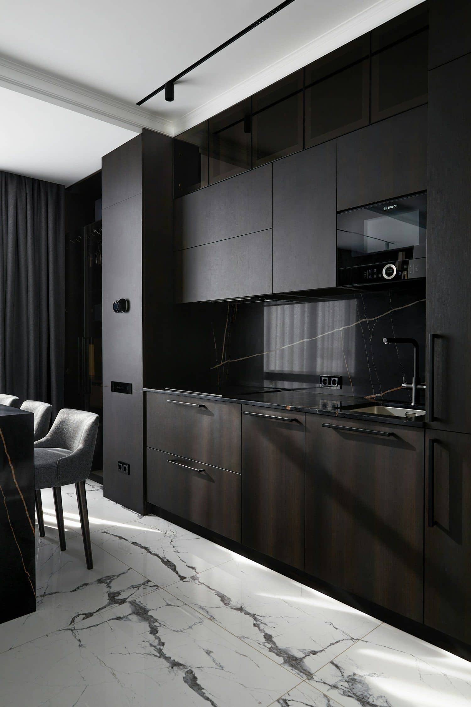 Dark luxury kitchen interior with veined marble and warm lighting