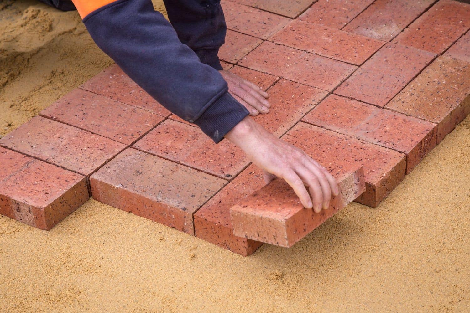 Hands laying premium interlocking pavers